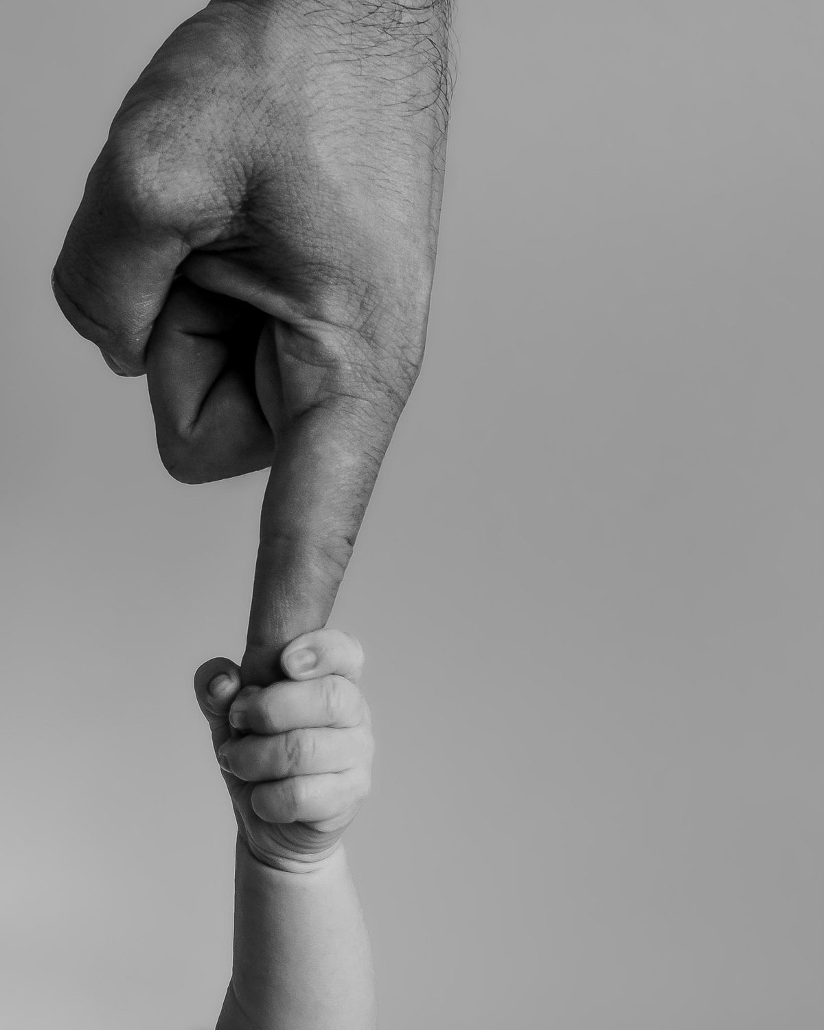 A newborn's tiny hand gripping a parent's finger