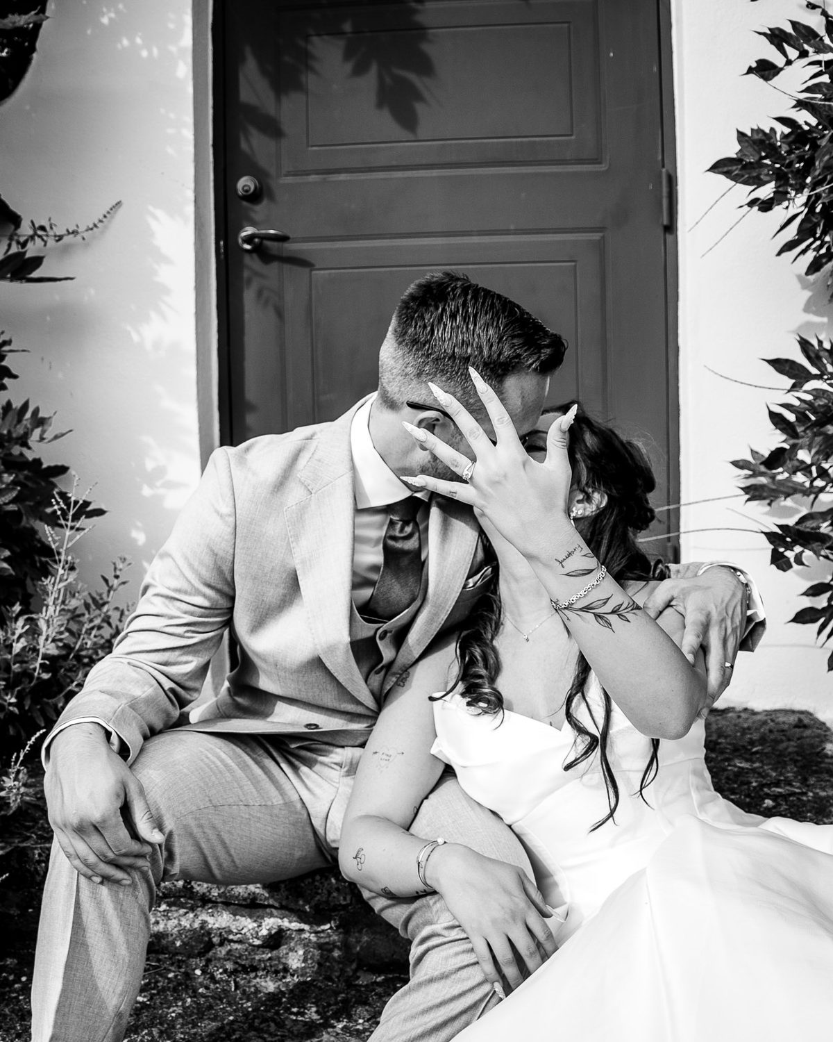 Couple kissing on stone steps, the bride's hand with her ring in front of their faces